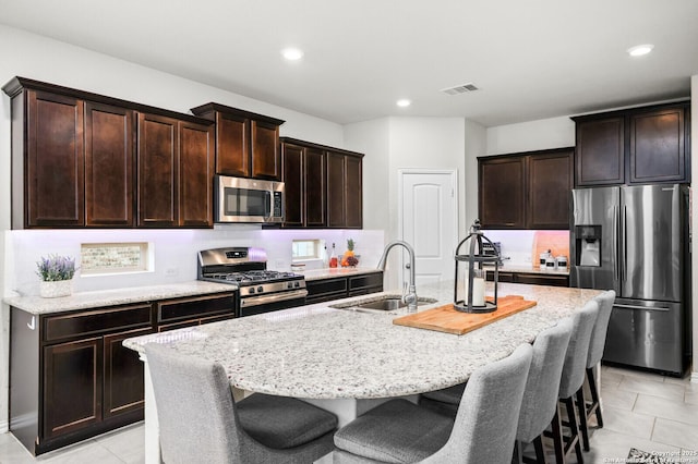 14447 Costa Leon, San Antonio, TX 78245 - kitchen featuring stainless steel appliances, a sink, a kitchen island with sink, tasteful backsplash, and a breakfast bar