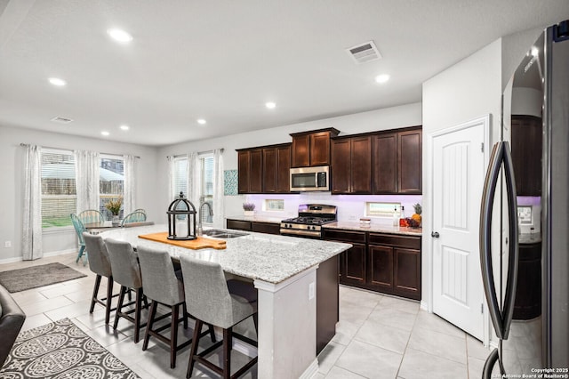 14447 Costa Leon, San Antonio, TX 78245 - kitchen with appliances with stainless steel finishes, a sink, a kitchen breakfast bar, an island with sink, and light stone counters