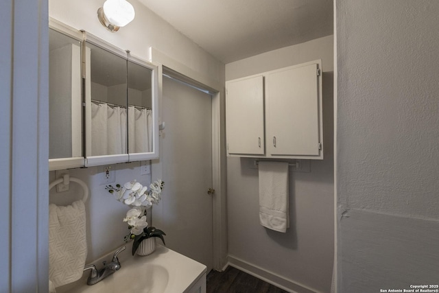 full bathroom with baseboards, vanity, and wood finished floors