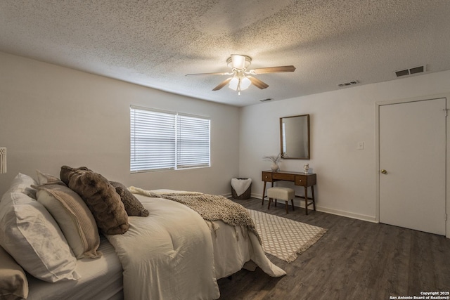 bedroom with a textured ceiling, ceiling fan, wood finished floors, and visible vents