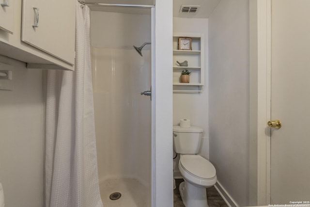 bathroom featuring toilet, baseboards, visible vents, and a shower stall