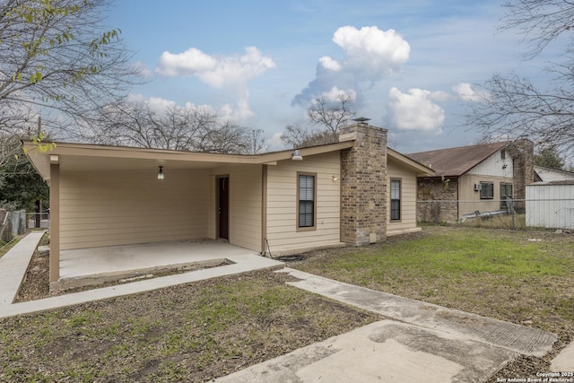 view of front of property featuring fence, a chimney, a front yard, and a carport