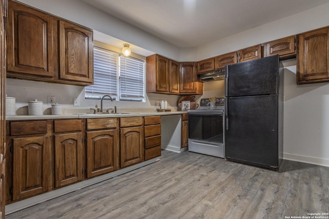 kitchen with light wood-style floors, freestanding refrigerator, range with electric stovetop, and under cabinet range hood