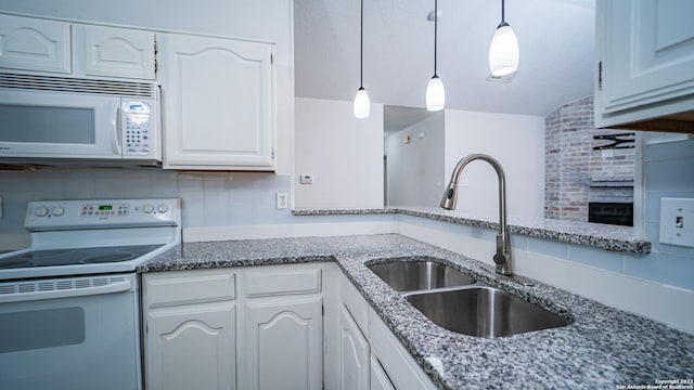 kitchen with tasteful backsplash, a sink, dark stone countertops, white appliances, and white cabinetry