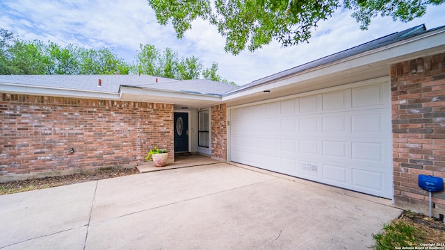view of front of property with brick siding, an attached garage, driveway, and roof with shingles