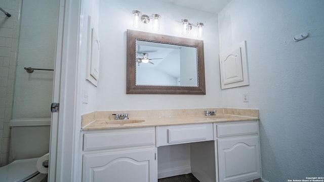 full bath featuring double vanity, toilet, ceiling fan, and a sink