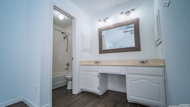 full bathroom with double vanity, wood finished floors, toilet, baseboards, and a sink