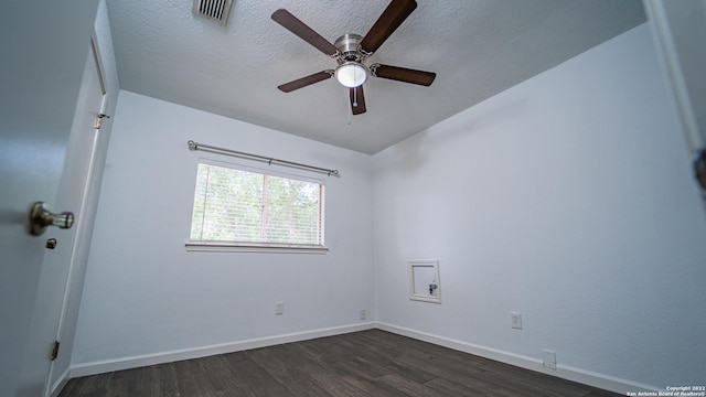 spare room featuring visible vents, a ceiling fan, dark wood-style flooring, and baseboards