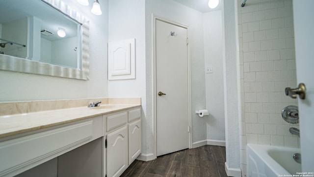 bathroom with baseboards, tub / shower combination, wood finished floors, and vanity