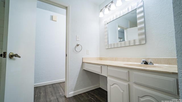 bathroom featuring vanity, baseboards, a textured wall, and wood finished floors