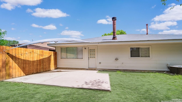 rear view of house with a patio, central AC unit, fence, and a yard