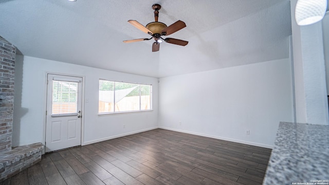 unfurnished living room with ceiling fan, vaulted ceiling, baseboards, and dark wood-type flooring