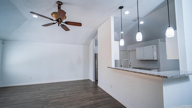 kitchen featuring white cabinets, light stone counters, dark wood finished floors, a ceiling fan, and lofted ceiling