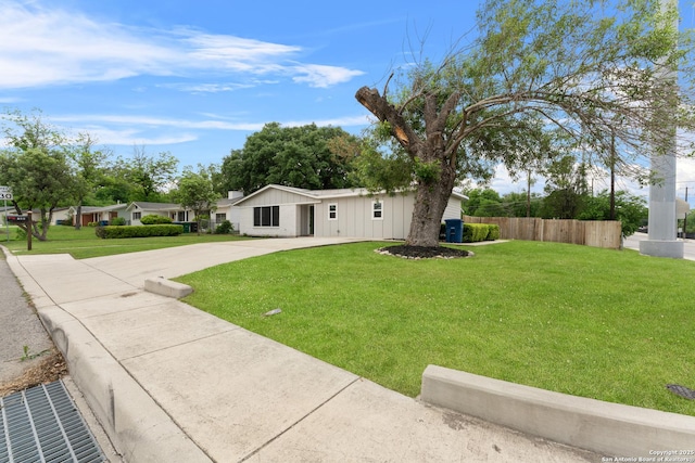 view of front of property featuring a front lawn, fence, and driveway