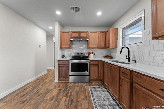 kitchen with a sink, stainless steel range with electric stovetop, decorative backsplash, under cabinet range hood, and visible vents