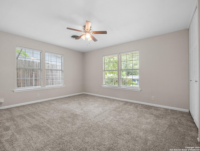 spare room with baseboards, ceiling fan, and carpet