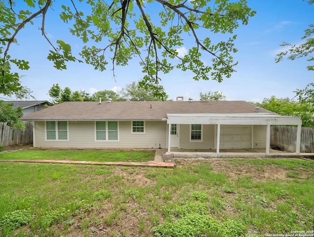 rear view of house with a yard, fence, and a carport