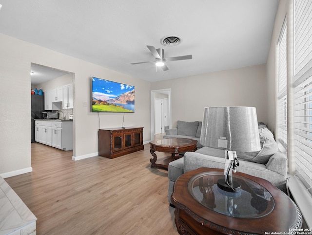 living area featuring ceiling fan, visible vents, a healthy amount of sunlight, and light wood-style flooring