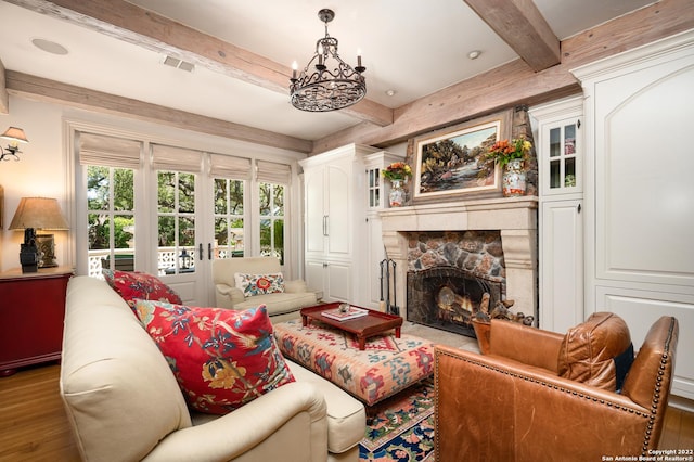 220 N School St, Boerne, TX 78006 - living area with an inviting chandelier, beam ceiling, a stone fireplace, wood finished floors, and visible vents