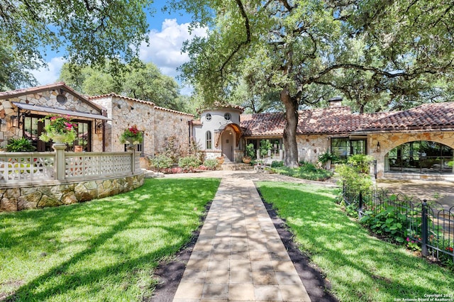 220 N School St, Boerne, TX 78006 - mediterranean / spanish-style house featuring a chimney, a front lawn, a tile roof, and stone siding