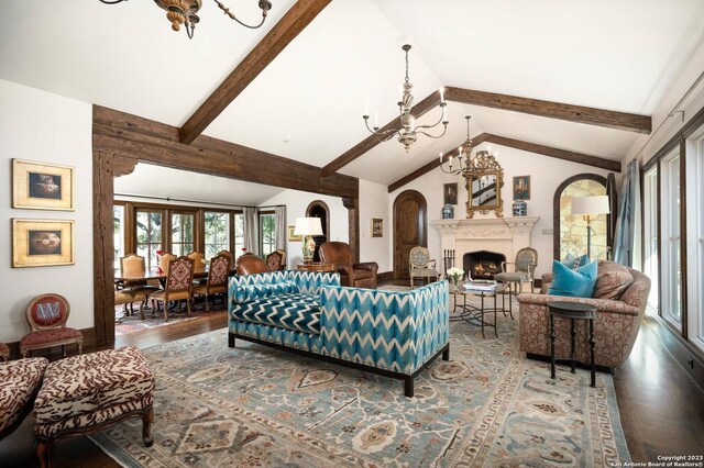 220 N School St, Boerne, TX 78006 - living room featuring wood finished floors, a wealth of natural light, arched walkways, lofted ceiling with beams, and a notable chandelier