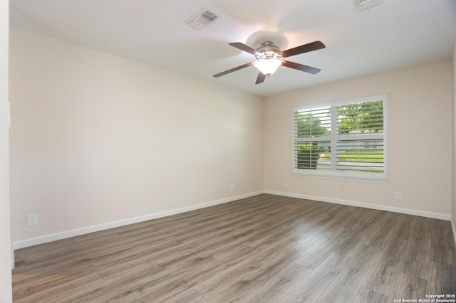 spare room featuring baseboards, ceiling fan, wood finished floors, and visible vents