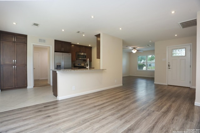 unfurnished living room featuring visible vents, a ceiling fan, baseboards, and light wood-style floors