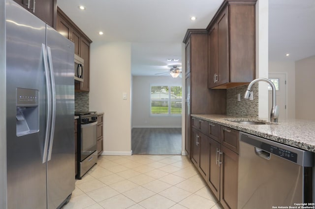 kitchen featuring decorative backsplash, light tile patterned flooring, light stone countertops, a sink, and appliances with stainless steel finishes