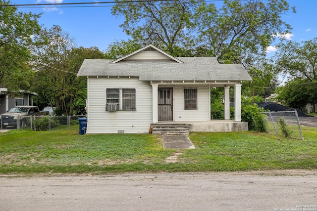 bungalow-style house featuring a porch, a shingled roof, fence, and a front yard