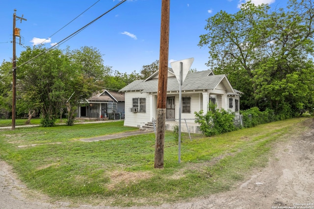 view of front of home featuring a shingled roof, cooling unit, a porch, and a front yard