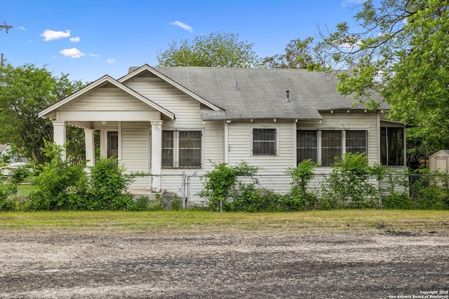 view of front of home with a sunroom, roof with shingles, and fence