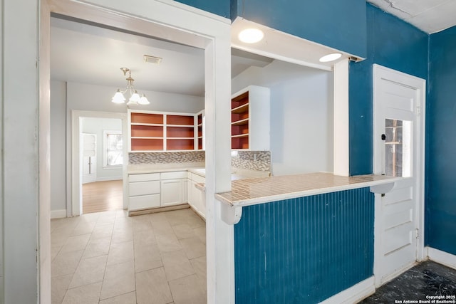 kitchen with open shelves, an inviting chandelier, white cabinetry, baseboards, and visible vents