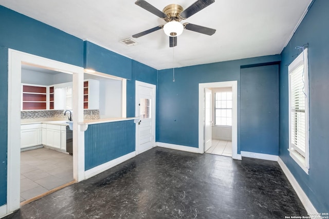 empty room with baseboards, a ceiling fan, and visible vents