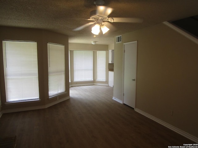 unfurnished room featuring baseboards, a ceiling fan, dark wood-style flooring, and visible vents