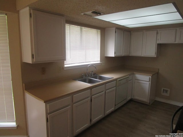 kitchen featuring visible vents, baseboards, a sink, dark wood finished floors, and dishwasher
