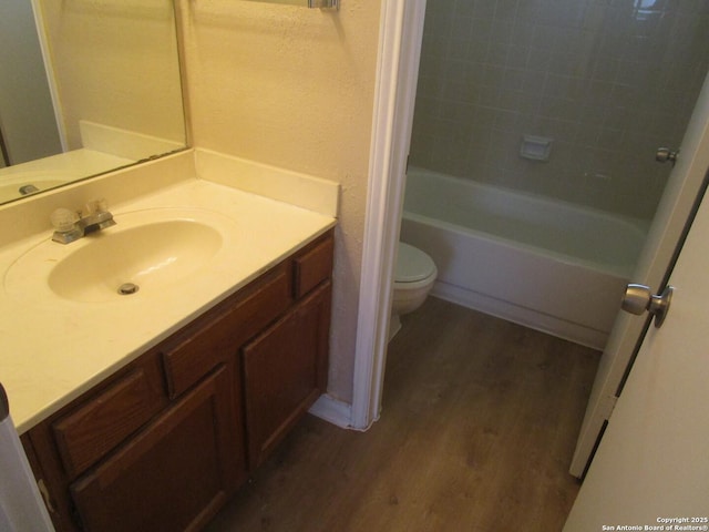 bathroom featuring toilet, shower / tub combination, wood finished floors, and vanity