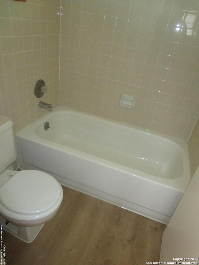 full bathroom featuring washtub / shower combination, toilet, and wood finished floors