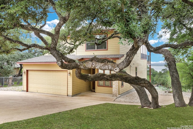 obstructed view of property with an attached garage, a front lawn, roof with shingles, and concrete driveway