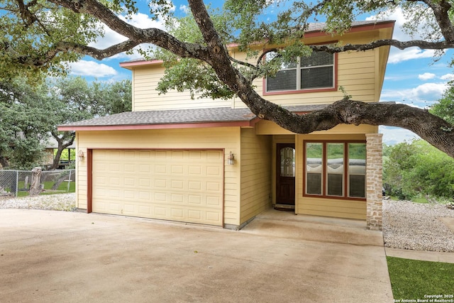 view of front of property featuring fence, driveway, and a garage