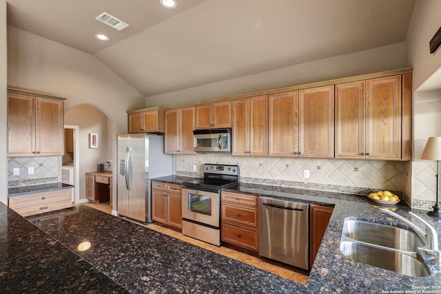 kitchen with backsplash, visible vents, appliances with stainless steel finishes, a sink, and lofted ceiling