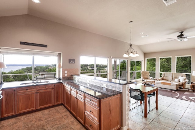 kitchen with light tile patterned flooring, a sink, ceiling fan with notable chandelier, a peninsula, and lofted ceiling
