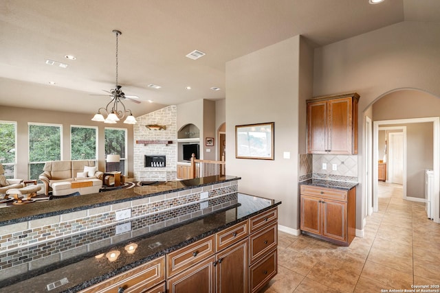 kitchen with baseboards, open floor plan, dark stone counters, and arched walkways