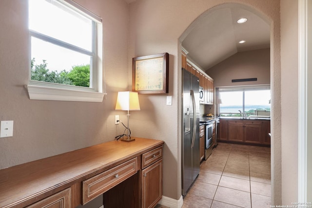 clothes washing area featuring a sink, arched walkways, light tile patterned floors, and recessed lighting