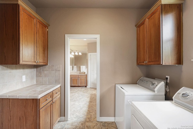 washroom with independent washer and dryer, light tile patterned flooring, and cabinet space