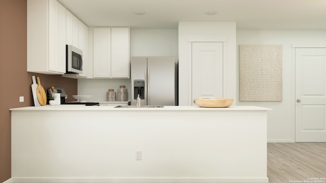 kitchen with appliances with stainless steel finishes, light wood finished floors, light countertops, a peninsula, and white cabinetry