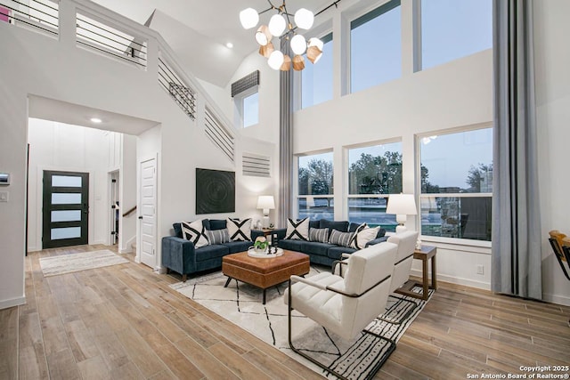 living room featuring baseboards, a chandelier, wood finished floors, and a towering ceiling