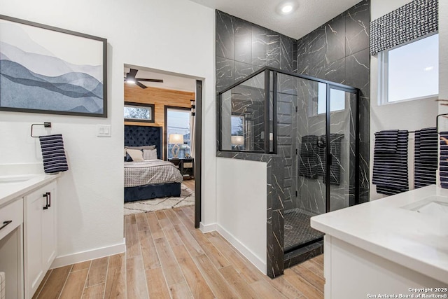 ensuite bathroom with vanity, wood finished floors, baseboards, a marble finish shower, and ensuite bath