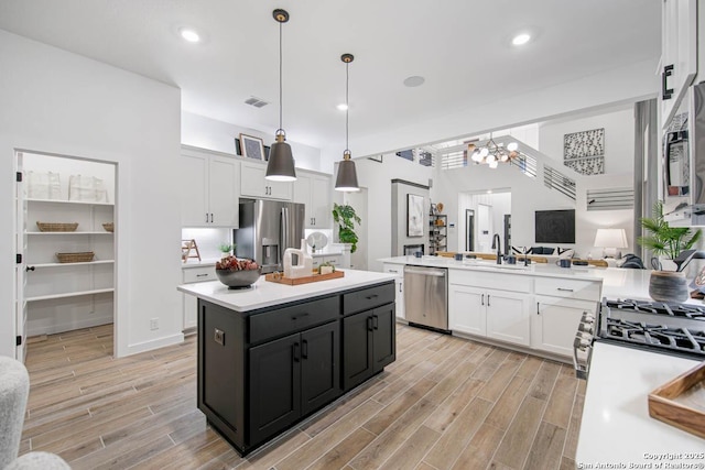 kitchen with light countertops, white cabinets, a sink, a notable chandelier, and stainless steel appliances