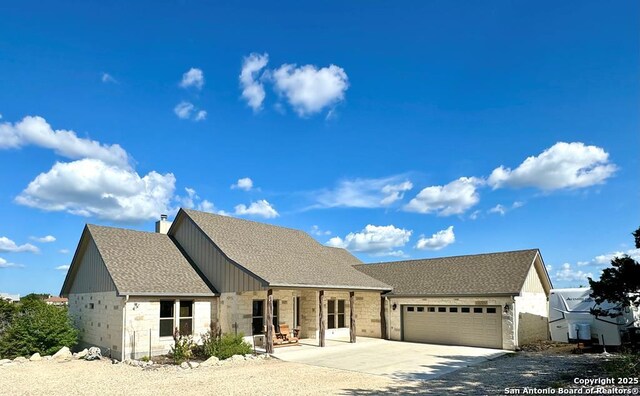 120 Sam Houston, Kerrville, TX 78028 - view of front of home with stone siding, a garage, concrete driveway, covered porch, and roof with shingles