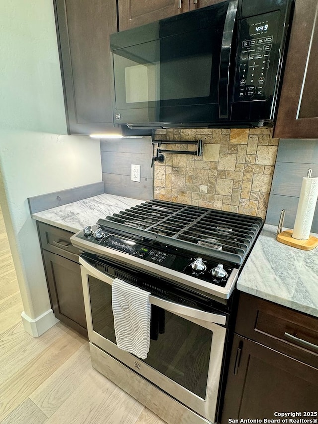 120 Sam Houston, Kerrville, TX 78028 - kitchen featuring stainless steel gas stove, black microwave, dark brown cabinets, light wood-style floors, and light stone counters